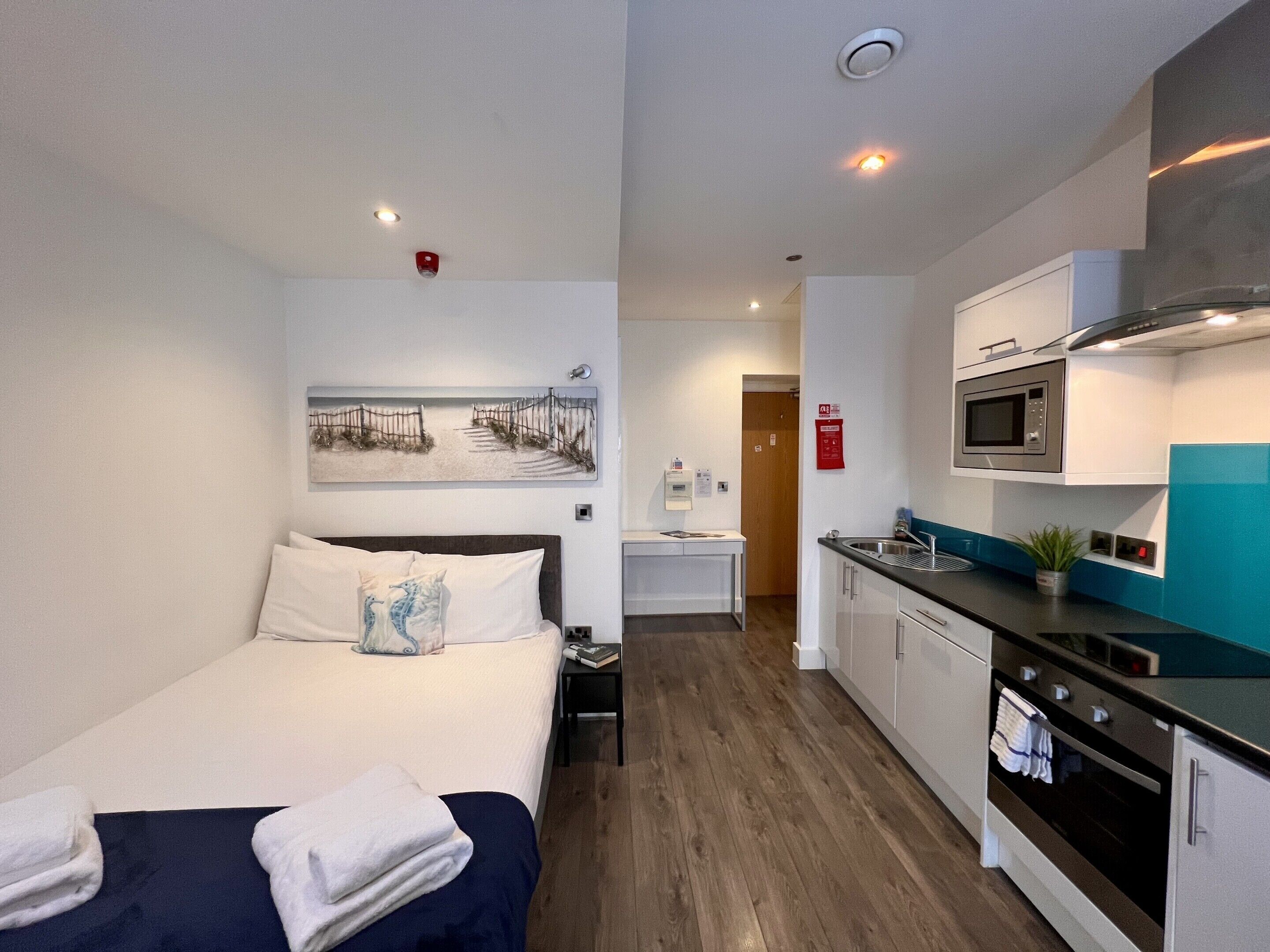 Ein kleines Hotelzimmer mit Bett, einer Küchenzeile und einem Badezimmer.