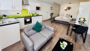 Un espacio habitable compacto con kitchenette, sofá, mesa de comedor y cama.