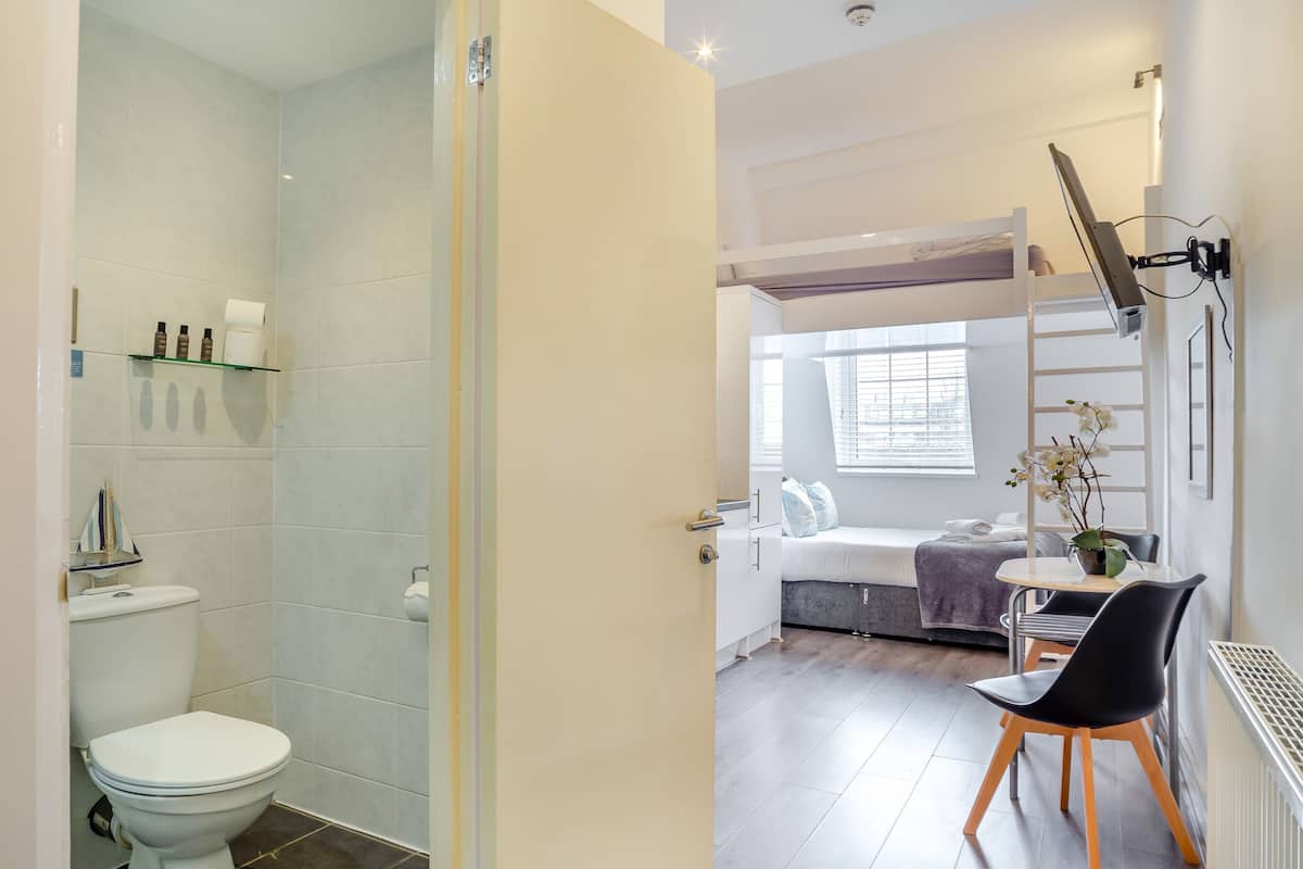 A modern bathroom with a shower, toilet, and a small seating area with a table and chairs.