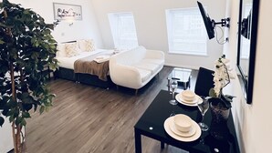 Una sala de estar moderna con un sofá, una mesa de comedor con sillas y una planta en maceta.