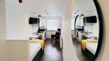 Una habitación de hotel moderna con un espejo grande, una cama, un escritorio y una kitchenette.
