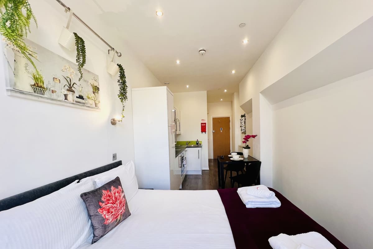 A hotel room with a bed, a desk, and a kitchenette.