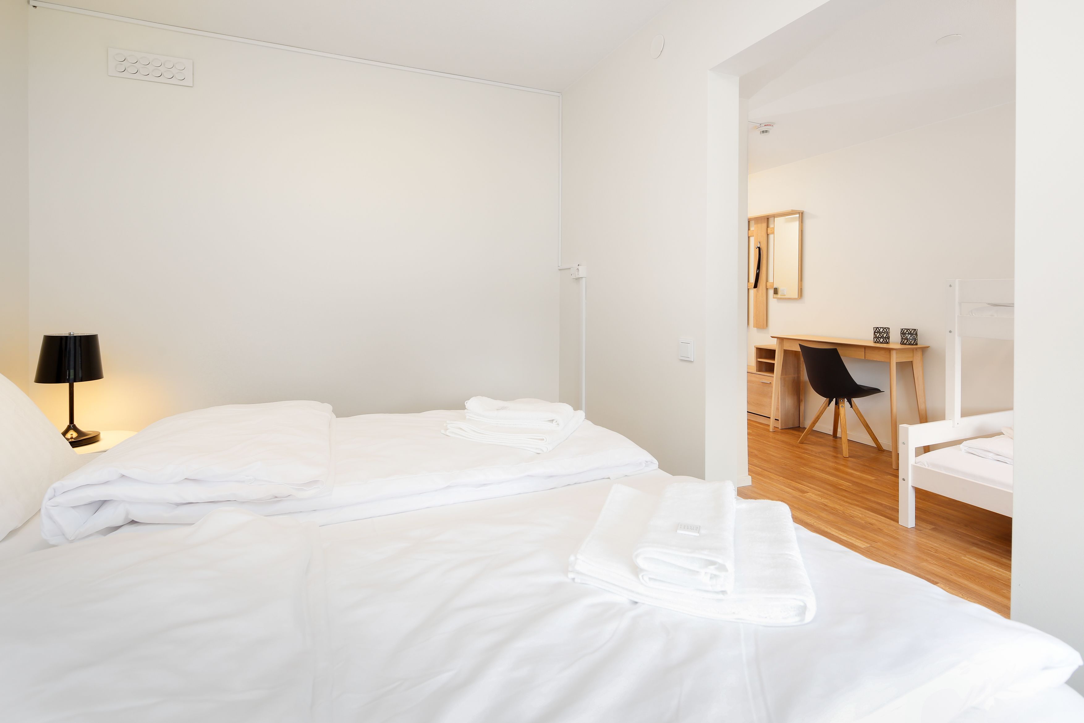 A hotel room with two beds, a desk, and a chair.