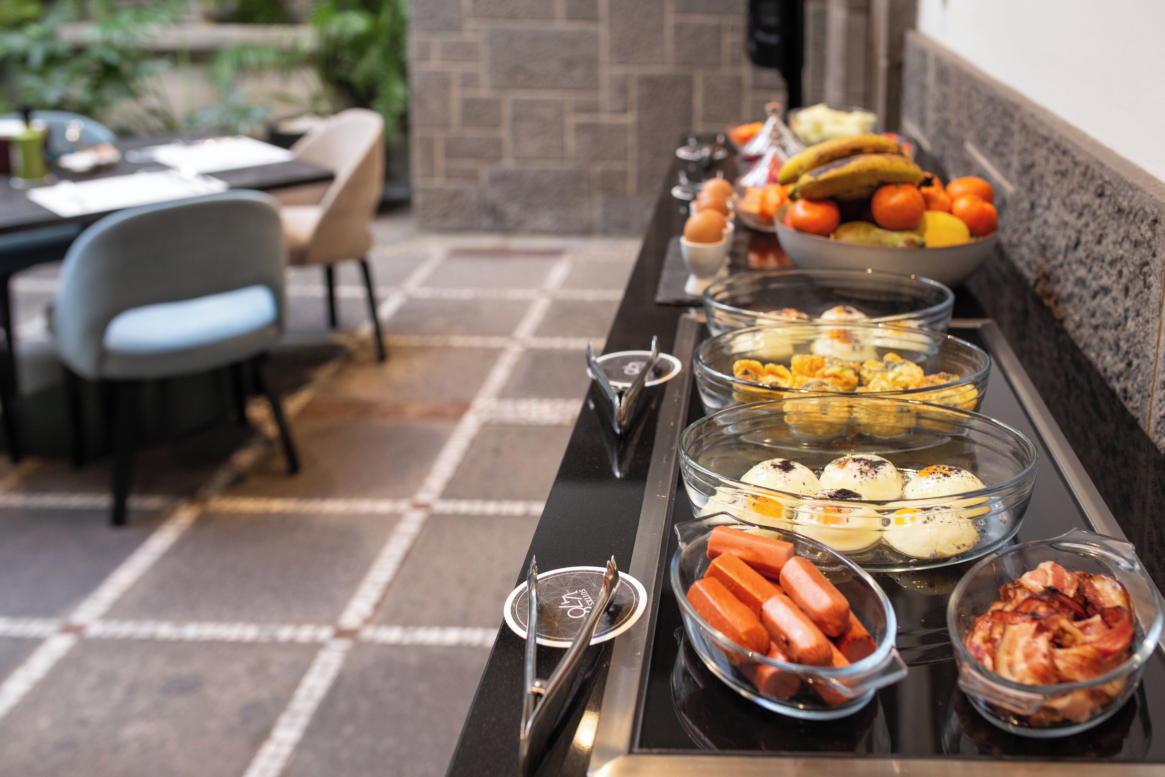 Un buffet proposant une variété de plats, notamment des hot-dogs, des œufs et des fruits.