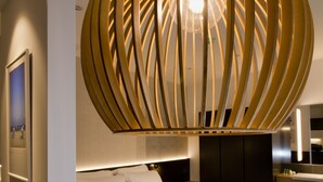 Habitación de hotel moderna con una cama grande, piso de madera y una lámpara circular única sobre la cama.