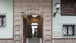 Entrada de un edificio con un arco de piedra, una escalera que lleva a una puerta y un letrero que indica 'SUITES 1478'.
