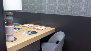 A modern, minimalist room with a wooden desk, a grey chair, and a lamp.