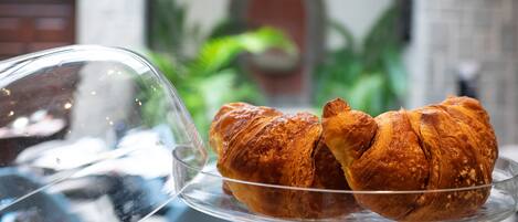 A glass display case with two croissants on a stand.