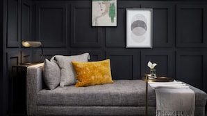 A dark-themed living room with a grey sofa, a lamp, and framed artwork on the wall. - Redford Hotel (New York)