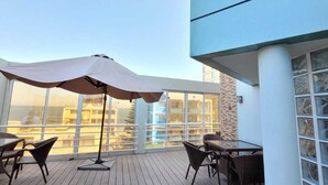 A wooden deck with outdoor furniture and a large umbrella.