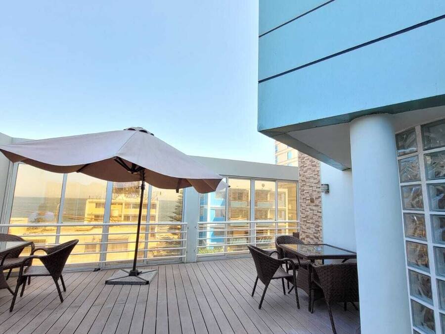 Una terraza de madera con mobiliario exterior y un gran paraguas.