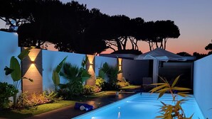 A modern outdoor pool area with a well-maintained lawn, surrounded by walls and plants. - Father's House Beach House (Sesimbra)