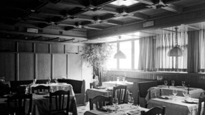 A restaurant with tables set for dining, featuring a high ceiling with exposed beams and pendant lighting. - Hotel Alpino (Cuasso Al Monte)