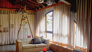A cozy living room with a sofa, a coffee table, and a decorative tree. - Hotel Alpino (Cuasso Al Monte)