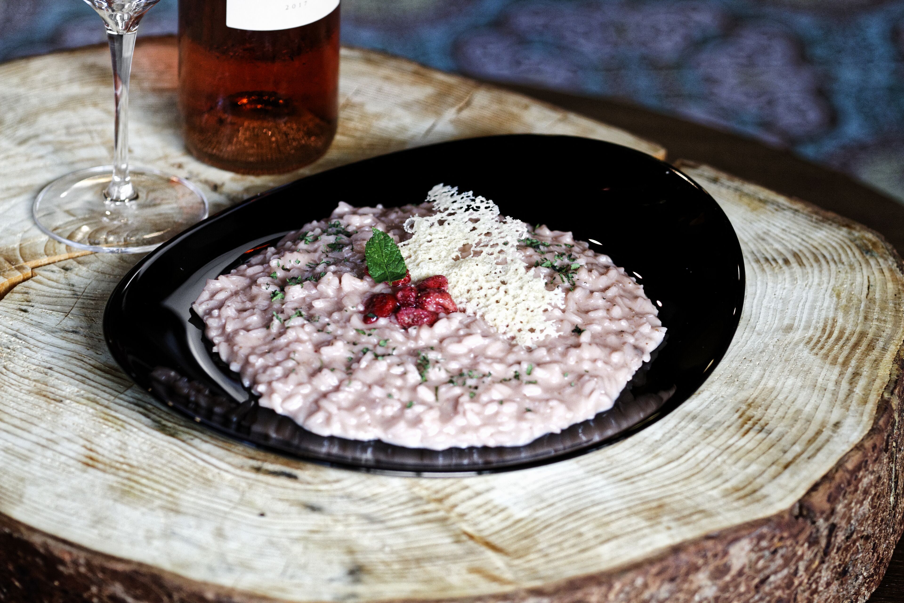 Une assiette de nourriture sur une table en bois, avec un verre et une bouteille en arrière-plan.
