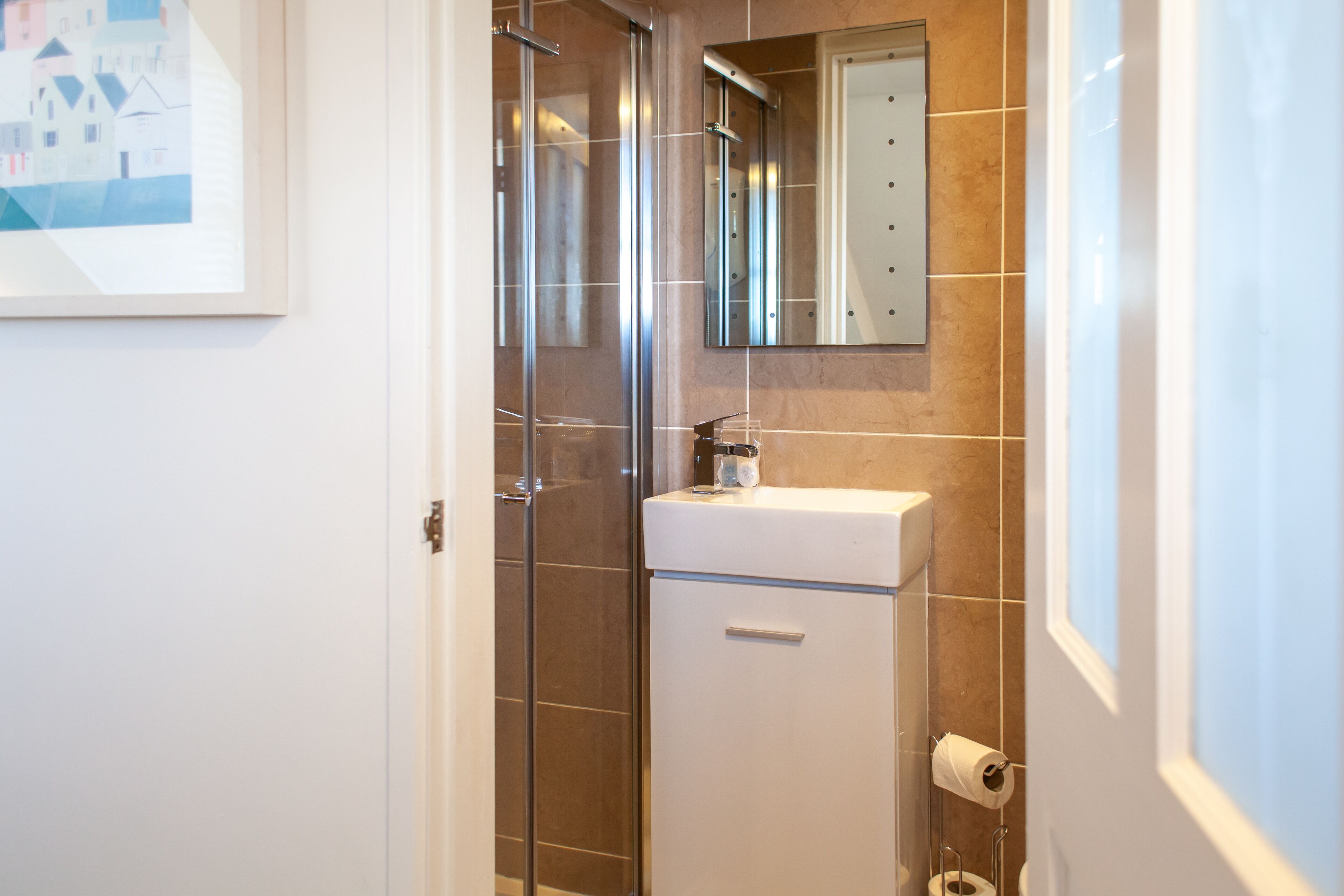 A bathroom with a glass shower enclosure, a white sink, and a mirror above it.
