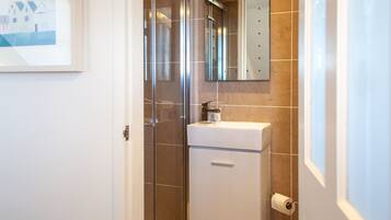 A bathroom with a glass shower enclosure, a white sink, and a mirror above it.