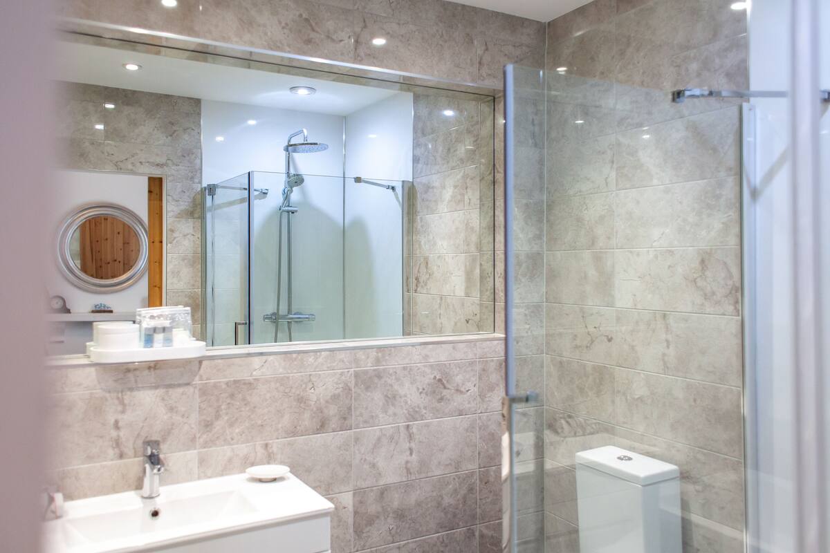 A modern bathroom with a glass-enclosed shower, a sink, and a toilet.