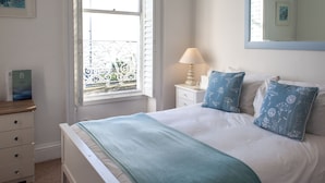 Een keurig opgemaakt slaapkamer met een bed, nachtkastje met lamp, raam met uitzicht en een kledingkast.