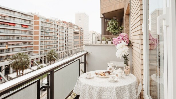 A balcony with a table set for tea, overlooking a cityscape with high-rise buildings. - DUPLEX IN GRAN VIA, GARAGE AND WIFI (Logroño)