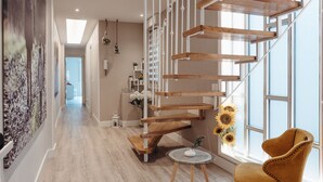 A modern interior with a wooden staircase, a round table with a vase, and a yellow armchair by a large window. - DUPLEX IN GRAN VIA, GARAGE AND WIFI (Logroño)
