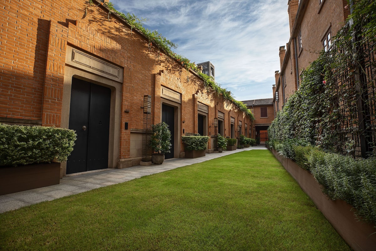 A courtyard with brick buildings, a paved walkway, and green landscaping.