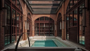 A pool area with a glass-enclosed pool, brick walls, and large windows. - Capella Shanghai, Jian Ye Li (Shanghai)