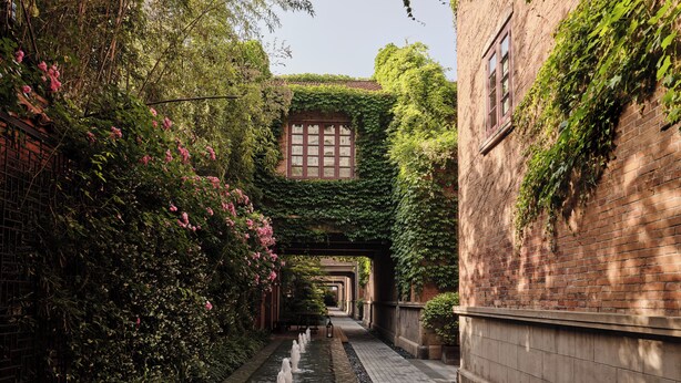 A narrow alley with a water feature, brick walls, and greenery. - Capella Shanghai, Jian Ye Li (Shanghai)