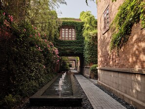 A narrow alley with a water feature, brick walls, and greenery. - Capella Shanghai, Jian Ye Li (Shanghai)