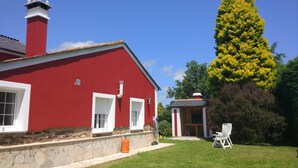 Ein rotes Haus mit steinernem Fundament, weißen Fenstern und einem Schornstein.