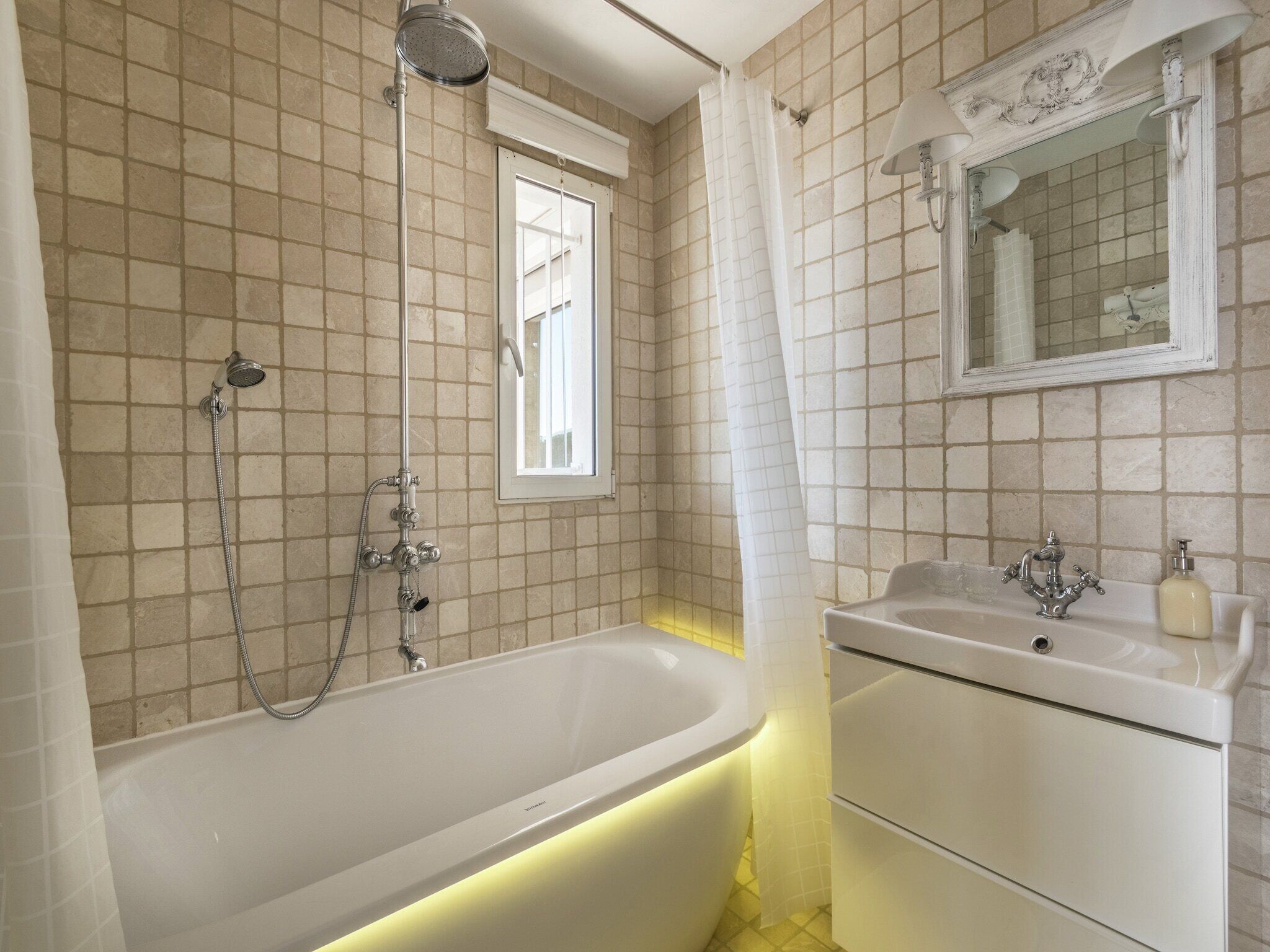 A bathroom with a bathtub, a shower, a sink, and a mirror.