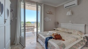 A bedroom with a bed, a bench outside the door, a beach sign, and an air conditioning unit. - Villa in Les Issambres near the Sea (Les Issambres)