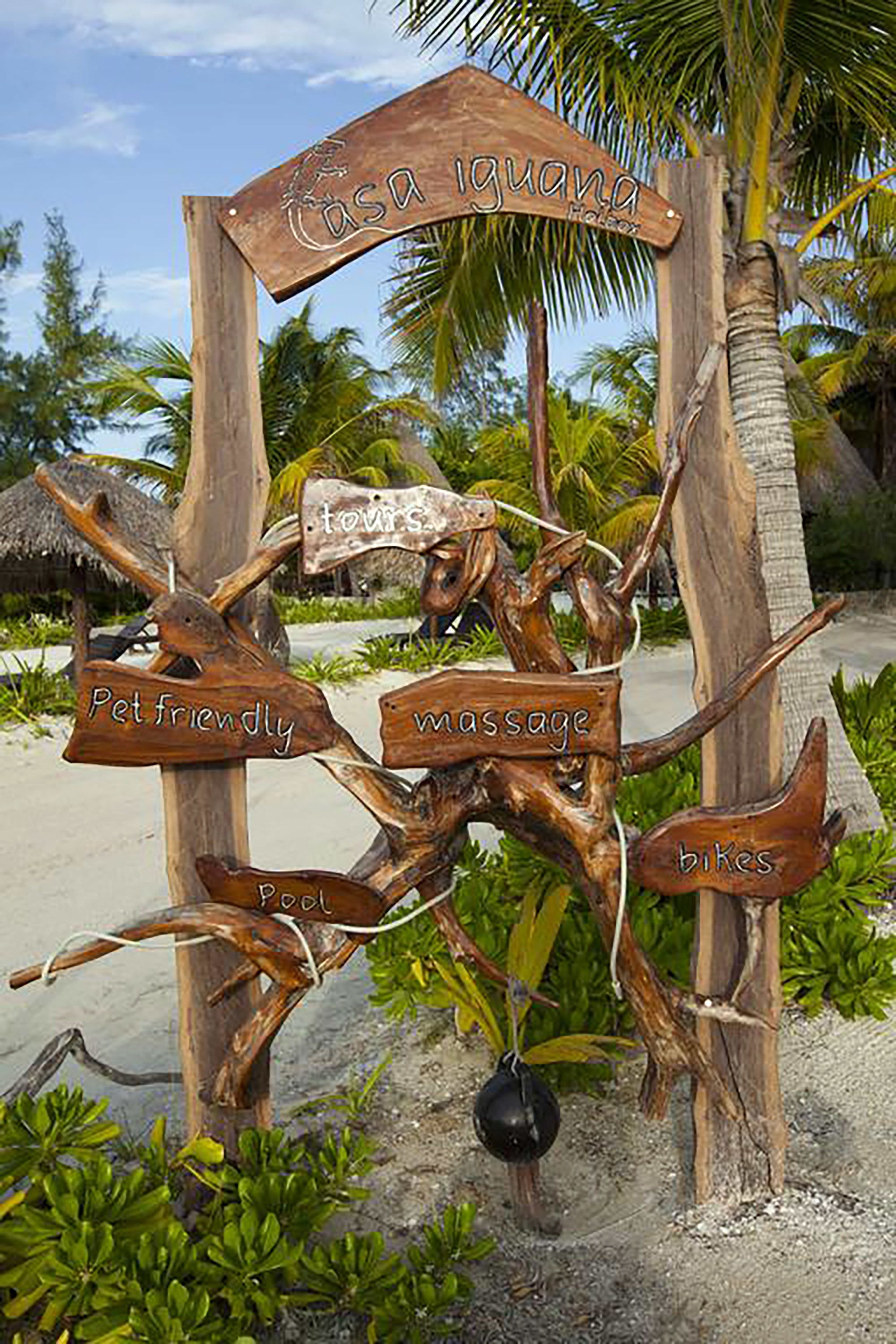 A wooden sign with 'Casa Iguana' and amenities like 'pet friendly,' 'massage,' and 'bikes.'