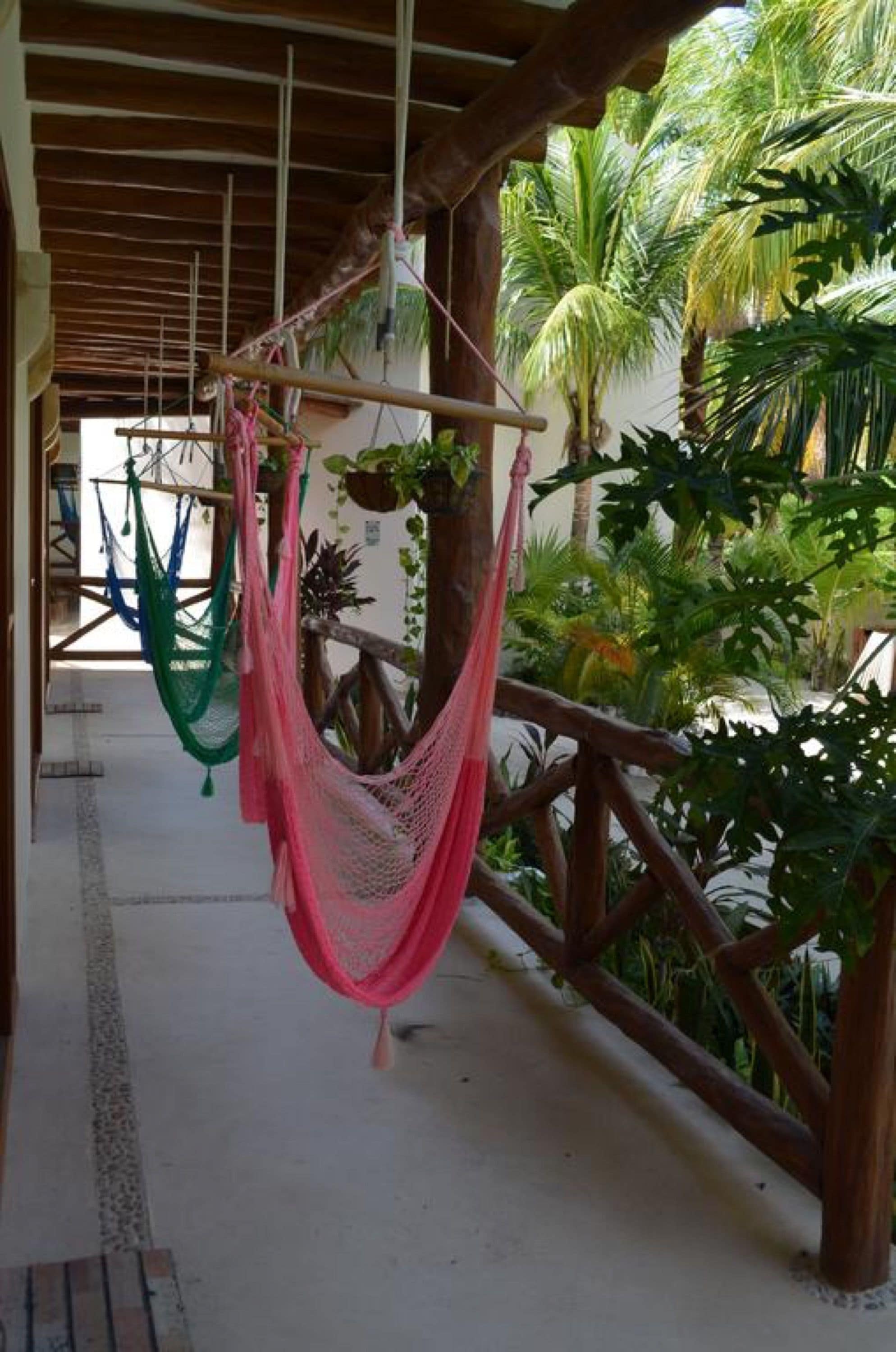 A covered outdoor area with wooden railings and hanging hammocks.