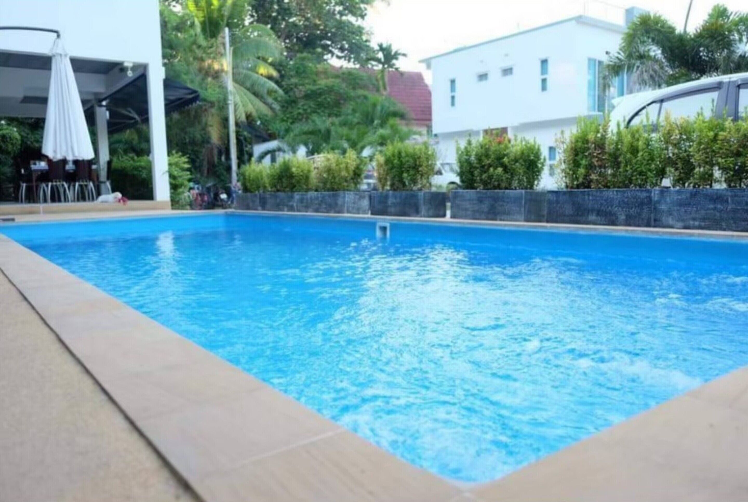 Una piscina con borde de baldosas, rodeada por un muro de piedra bajo y follaje.