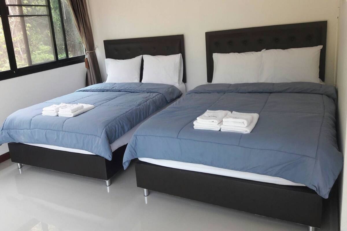Une chambre d’hôtel avec deux lits, chacun recouvert d’une courtepointe bleue et doté d’oreillers blancs.