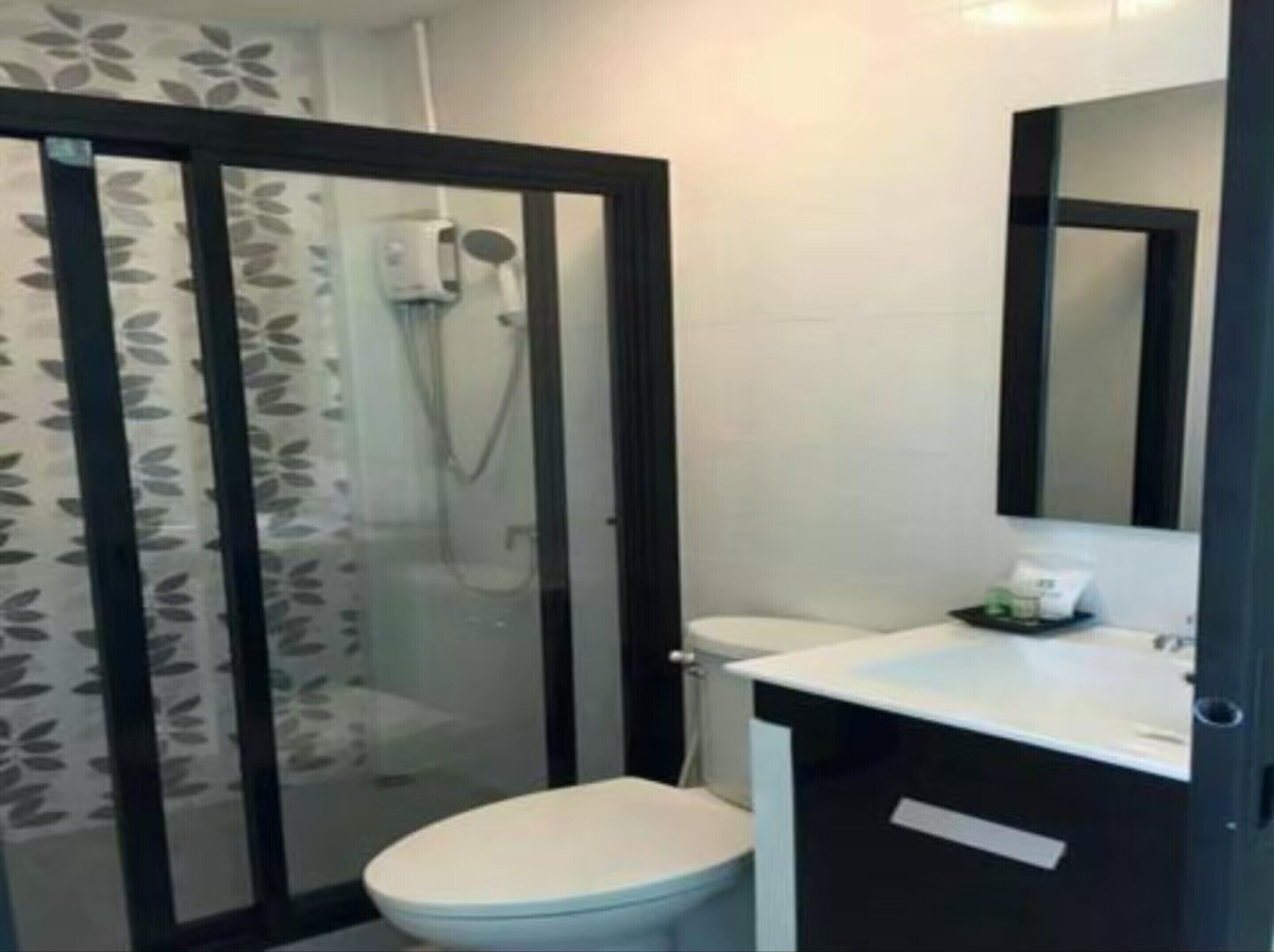 A modern bathroom with a glass shower enclosure, a white toilet, and a sink with a mirror above it.