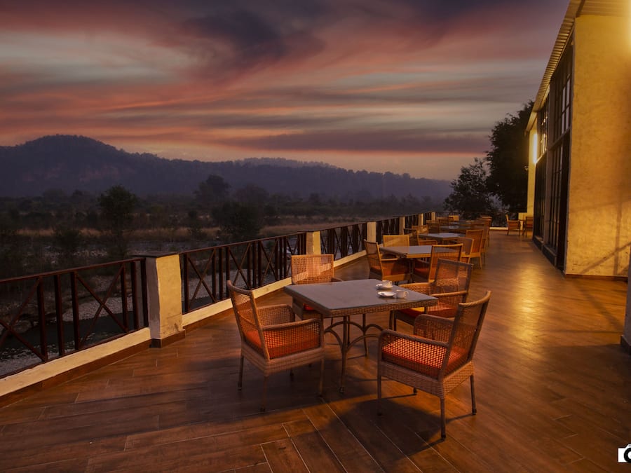 A terrace with wicker furniture and a view of a mountainous landscape.