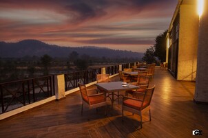 Una terraza con mobiliario de mimbre y vistas a un paisaje montañoso.