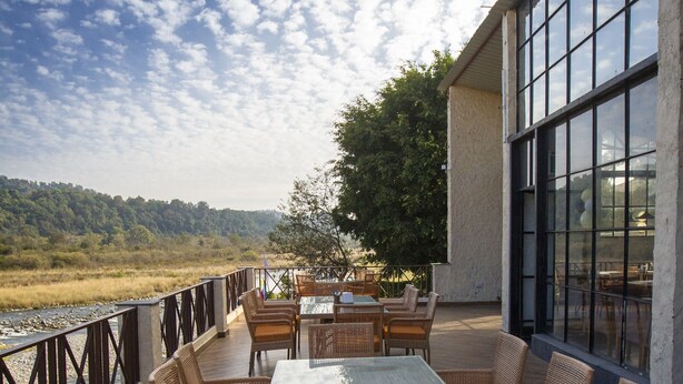 Una terraza con mobiliario de mimbre y una mesa de vidrio con vista al río.