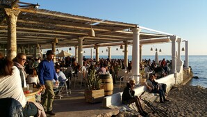 Ein Restaurant am Meer mit Terrassensitzmöglichkeiten, Blick auf das Meer und einem reetgedeckten Dach.
