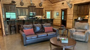 Ein gemütliches Blockhaus-Interieur mit einem Ledersofa, einem runden Couchtisch und einem Ledersessel.