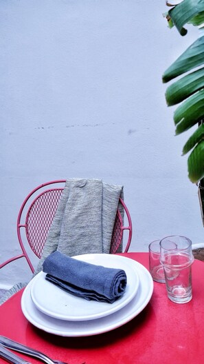 A table with a red tablecloth, a white plate with a folded napkin, and two clear glasses.