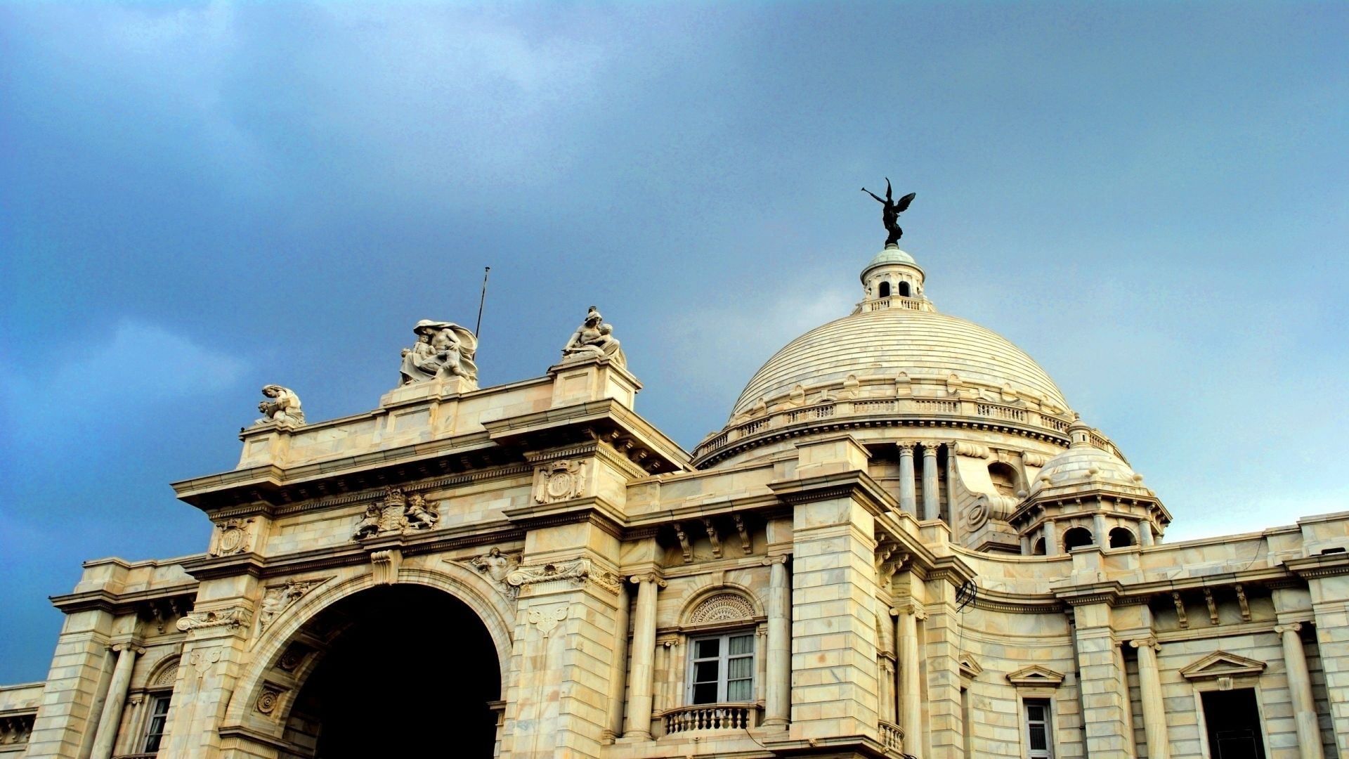 A grand building with a large dome and statues on the roof.
