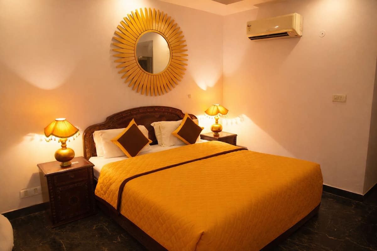Une chambre d’hôtel avec un grand lit, deux lampes de chevet, un miroir rond et un appareil de climatisation fixé au mur.