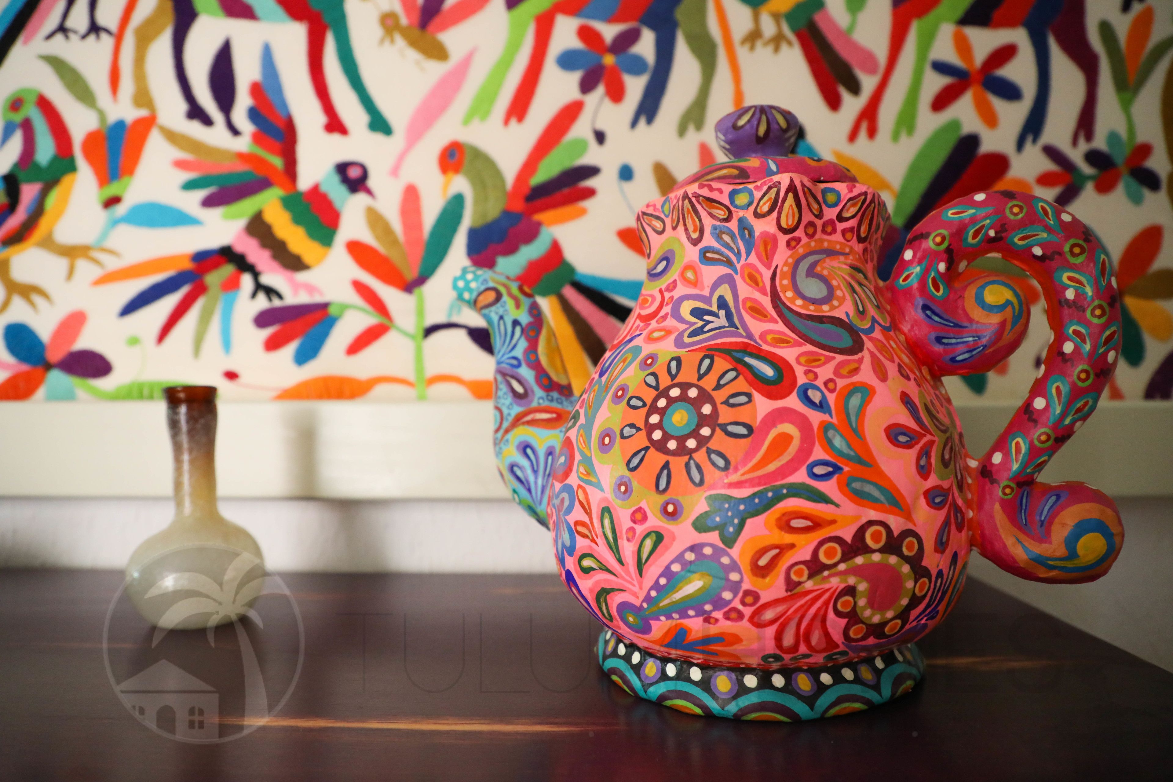 Una tetera colorida con motivos florales sobre una mesa.