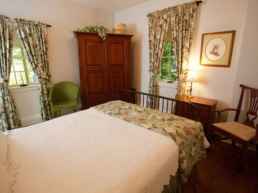 Une chambre à coucher avec un lit, une armoire en bois, une chaise et une lampe.