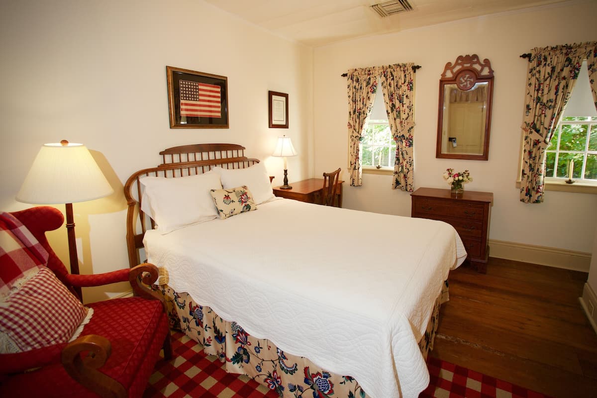 A neatly arranged bedroom with a bed, a chair, a table, and a dresser.