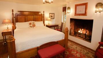 A traditional bedroom with a four-poster bed, a fireplace, and a red bench.