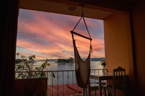 Una hamaca colgada en un balcón con vista a un atardecer sobre el agua.